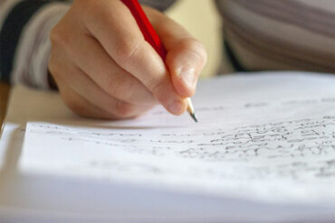 ruka píše do zápisníka na stole