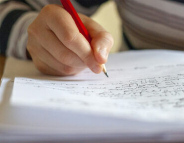 ruka píše do zápisníka na stole