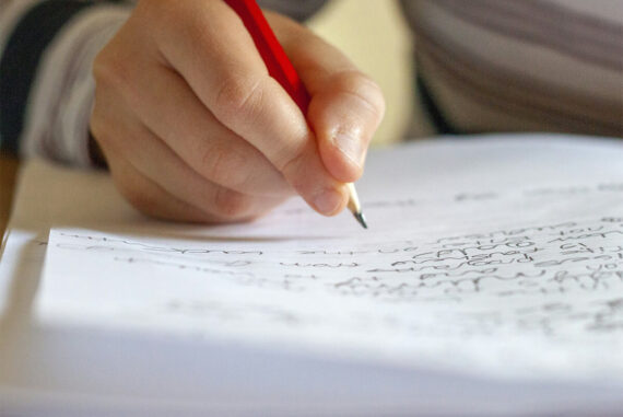 ruka píše do zápisníka na stole